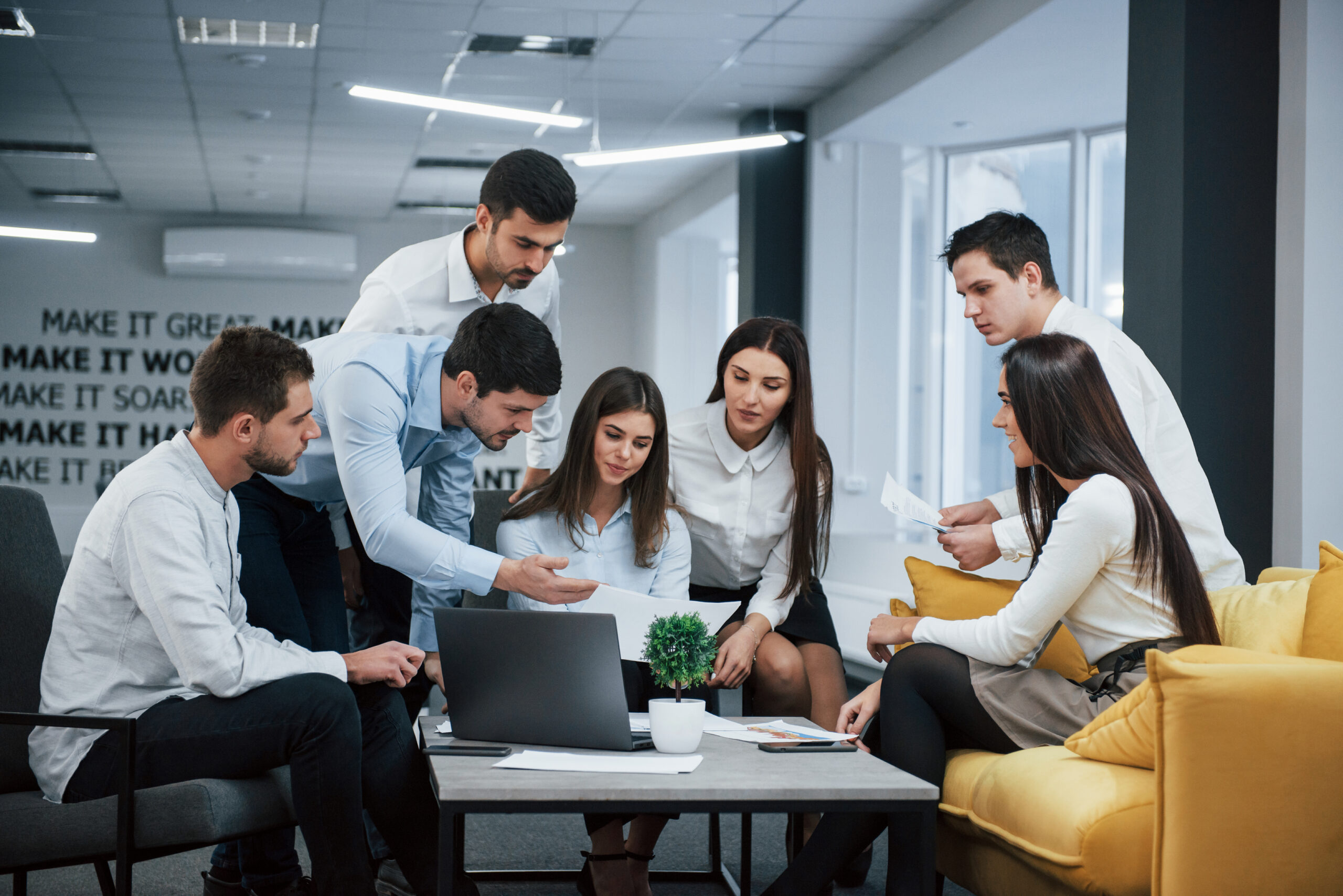 Guy shows document to a girl. Group of young freelancers in the office have conversation and working Guy shows document to a girl. Group of young freelancers in the office have conversation and working.